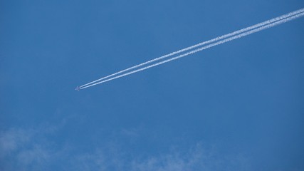 Aircraft flying through the sky blue, Condensing traces in the background.