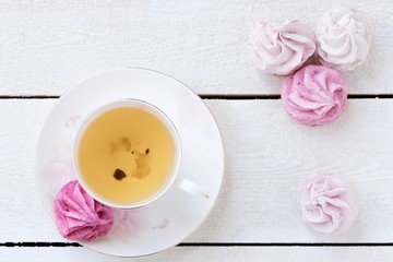 GREEN TEA  AND MARSHMALLOWS ON WHITE WOODEN BACKGROUND	