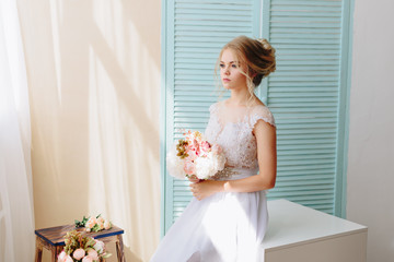 portrait of a beautiful girl with blue eyes and white hair with a bouquet of flowers and a white dress