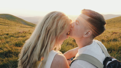 Loving couple sitting on a mountain meadow and enjoys the view of the sunset