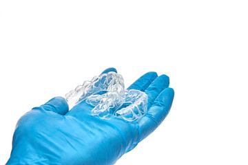 Hand is holding set of custom dental trays for bleaching teeth. Isolated on a white background