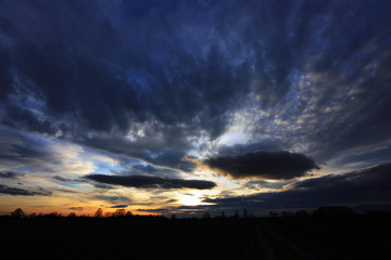 Burzowe chmury na błękitnym niebie w czasie zachodu słońca.