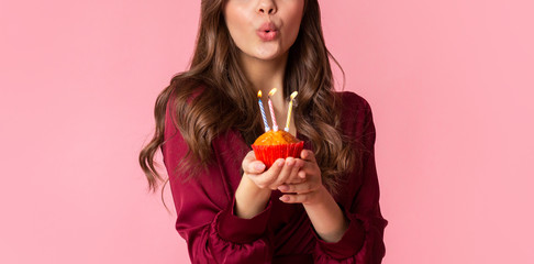 Unrecognizable woman blowing colourful candles on birthday cupcake - Powered by Adobe