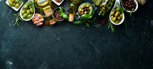 Fototapeten Olive oil, olives and spices on a black stone background. Top view. Free space for your text. © Yaruniv-Studio