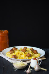 pasta with small fried meatballs balls on a dark wooden background