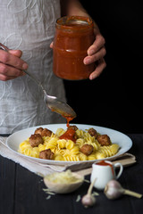 pasta with small fried meatballs balls on a dark wooden background