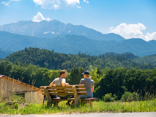 A couple sits on a bench and enjoys a beautiful view of the Alps
