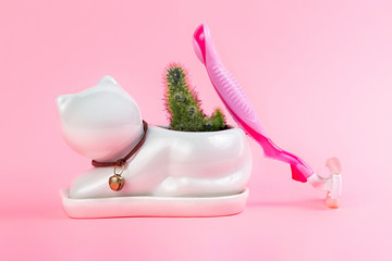 Cactus in a white flowerpot like cat and a nearby razor on a pink background. The concept of depilation and epilation. Copy space