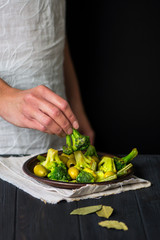 warm broccoli and green olives salad on dark wooden background