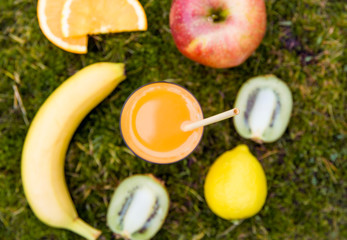 Bamboo drinking straw in mixed juice and lot of different sweet fruits around on natural soft green moss outdoors. Shallow depth of field and copy space. Zero waste lifestyle concept. Top view.