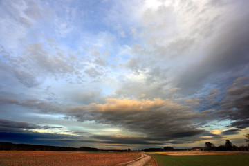 Burzowe chmury, obłoki na błękitnym niebie w czasie zachodu słońca.