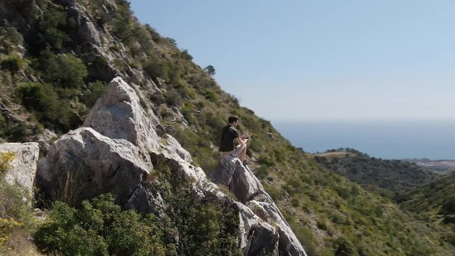 Caucasian man in the mountains, taking photos of the Marbella horizon.