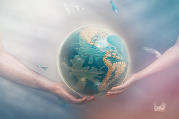 The concept of environmental protection and Earth day. Female and male hands hold the globe of planet Earth, surrounded by garbage