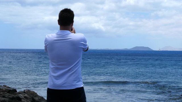 Man taking seascape picture with smartphone. Static