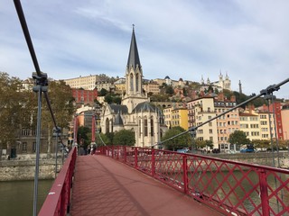 Obraz premium The Saint-Georges Roman Catholic church seen from the Paul Couturier bridge in Lyon, France. In the background the Basilica of Notre-Dame de Fourvière and the Metallic tower of Fourvière