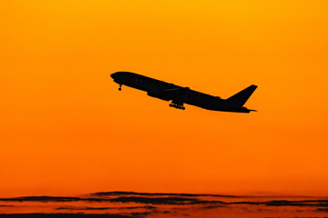朝焼けの中離陸するジェット旅客機