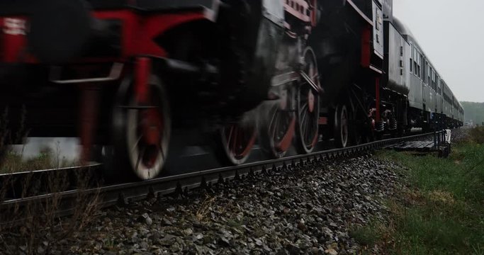 Historic steam train locomotive with railroad passenger wagons in the countryside passing by
