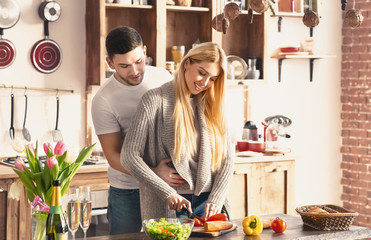 Romantic young couple embracing and cooking together