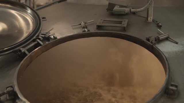 Beer mixes in a steel brewing fermentation vat inside a craft brewery slider shot slow push in