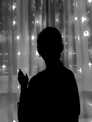 Silhouette of a girl on the background of luminous lights of a garland.