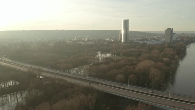 Cinematic drone / aerial shot of  the post tower skyscraper in bonn with rhe river fhine and the konrad-adenauer bridge with traffic at the golden hour, 25p