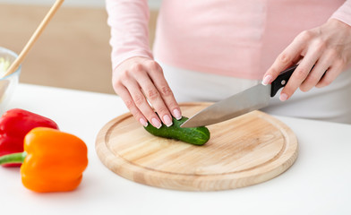 Girl cutting fresh vegetables for salad at kitchen top