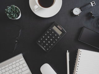top view of office desk table with notebook, plastic plant, calculator and keyboard on black background, graphic designer, Creative Designer concept.