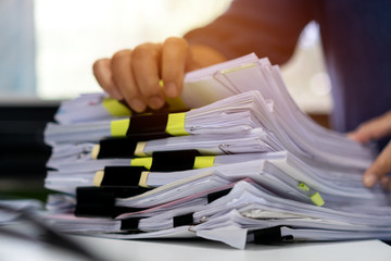 Stacks documents of paper files, Businessman hands working in messy bureaucracy and searching information on office, Accounting budget report file, arranging unfinished of paperwork on busy overwork - obrazy, fototapety, plakaty