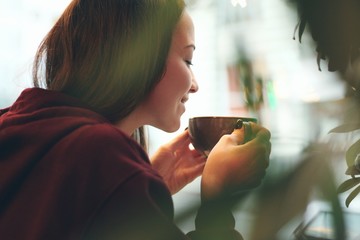 Caucasian young woman enjoying coffee drinking in cafe, close up