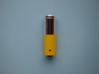 Closeup silver and yellow AA size alkaline batterie isolated on blue background top view with copy...