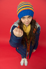 Punch in face. Threatening fist. Little girl wear winter clothes red background. Childhood concept. Emotional girl long hair knitted hat. Teen girl casual style. Emotions mood. Bullying prevention