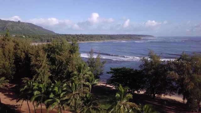 Aerial Footage of Hawaii drone flying from beach to the ocean waves touching shoreline with Island and mountains the in background. Hanalei Bay.