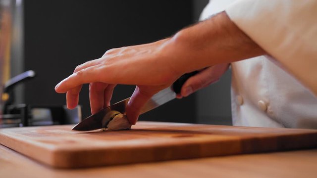 the cook is cuting garlic on a wooden board.