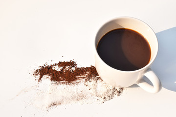Black coffee in a white cup Coffee powder strewn loss Put on the table a white background
