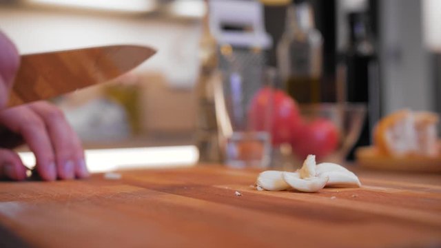 cook peels garlic on a wooden board.