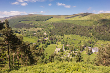 View from above of the Early Medieval monastic settlement with Round Tower, nestled in a woodland glacial valley at Glendalough National Park, County Wicklow, Ireland.
