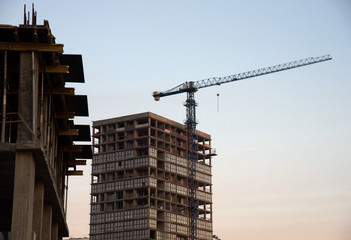 Fototapeta premium Hydraulic luffing jib tower cranes and workers being poured concrete into foundation. Cement pouring into formwork of building at construction site. Tower cranes constructing a new residential build