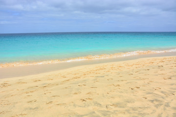 Fototapeta na wymiar Natural background, a beautiful sandy beach and turquoise, blue calm. ocean, sea with a clear horizon on a sunny day on Sal Island in Cape Verde, Cabo Verde