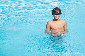 young asian boy playing at the swimming pool