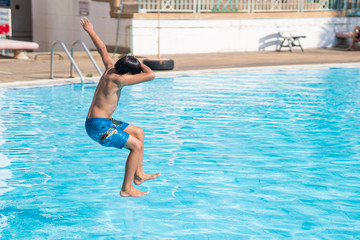 young asina boy jumping into the swimming pool