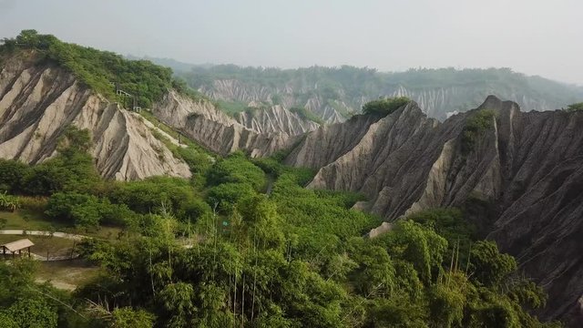 Cinematic Aerial View on Lake, Green Forest and Grey Mudstone Hills in Tianliao Moon World Landscape Park, Taiwan