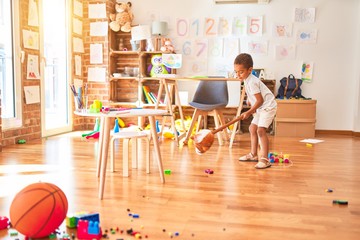 Beautiful african american toddler playing with horse toy with stick around lots of toys at kindergarten