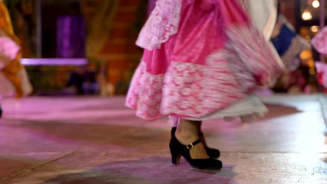 Closeup of woman’s dress and shoes as she does a Mexican folk dance on stage.