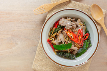 top view of stir fried sizzle duck meat in a ceramic dish on wooden table. asian homemade style food concept.