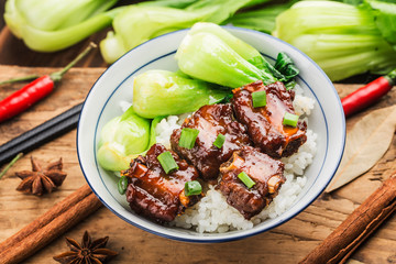 A bowl of rice with ribs in brown sauce