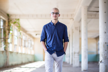 Cute, young man in blue shirt and white pants with eyeglasses. Teen fashion