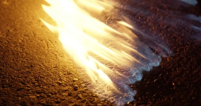 Close up shot of a flame on the ground / on a road / street at night 25p
