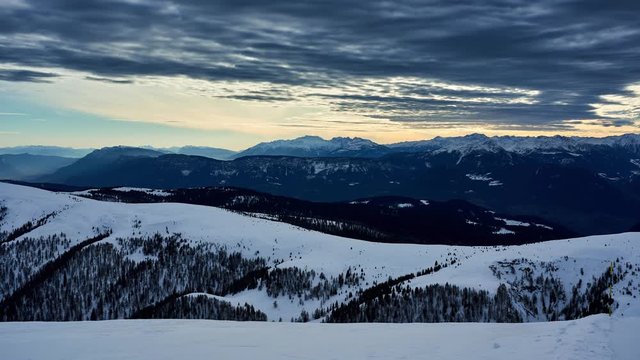 Early sunset time lapse of the snow capped alps in winter from the top of Mittager. Italy
