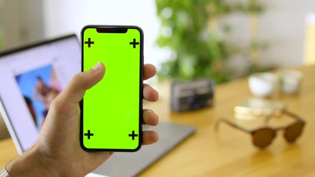 Man scrolls on phone with chroma key screen, travel themed