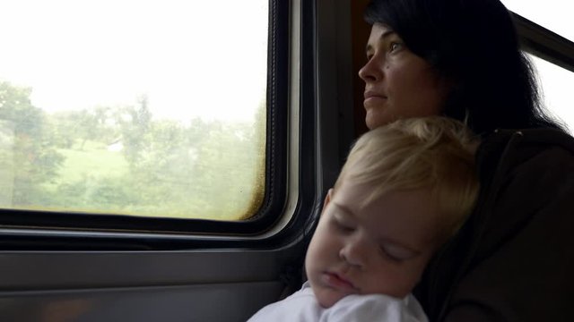Tired Depressed Young Mother With Child. Poor Refugee Family Traveling by Old Dirty Budget SuburbanTrain. Passenger Carriage